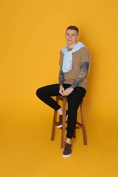 Smiling Young Man Tattoos Sitting Stool Yellow Background — Stock fotografie