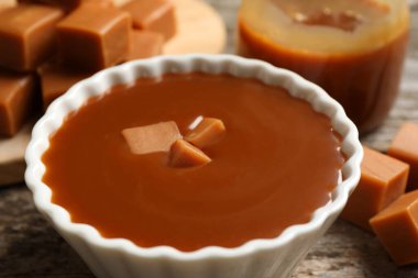 Tasty salted caramel with candies on table, closeup