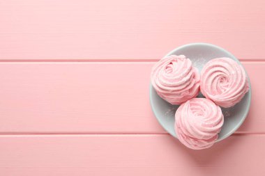 Plate with delicious zephyrs on pink wooden table, top view. Space for text