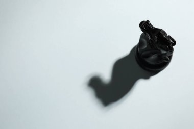 Black wooden chess knight on light grey background, above view. Space for text