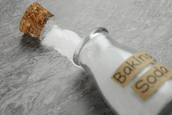 Overturned Glass Bottle Baking Soda Grey Table Closeup — стоковое фото