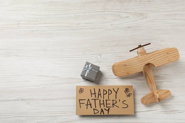 フレーズ付きのカード白い木製の背景に幸せな父の日 おもちゃの飛行機やギフトボックス フラットレイアウト テキストのスペース — ストック写真