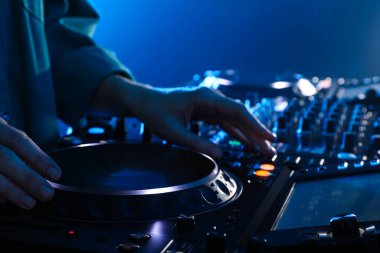 DJ, gece kulübünde modern konsol karıştırıcısında müzik yaratıyor.