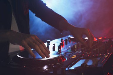 DJ, gece kulübünde modern konsol karıştırıcısında müzik yaratıyor.