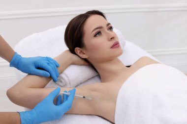 Kozmetik uzmanı klinikte genç bir kadının koltuk altına iğne yapıyor. Hiperhidroz tedavisi