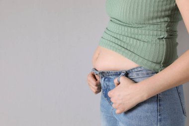 Woman wearing tight clothes on light grey background, closeup view with space for text. Overweight problem