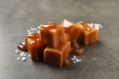 Gri masada soslu ve deniz tuzlu lezzetli karamel şekerlemeleri, yakın plan.
