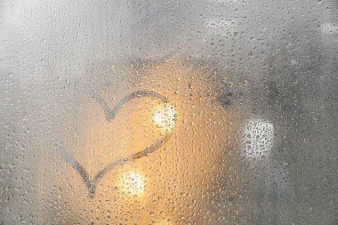 Sisli pencereye kalp çizilmiş. Yağmurlu hava