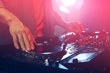 DJ, gece kulübünde modern konsol karıştırıcısında müzik yaratıyor.