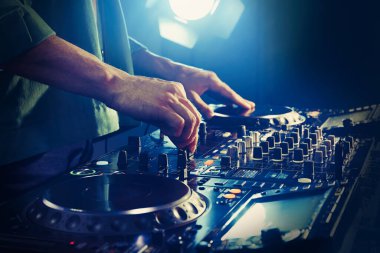 DJ, gece kulübünde modern konsol karıştırıcısında müzik yaratıyor.