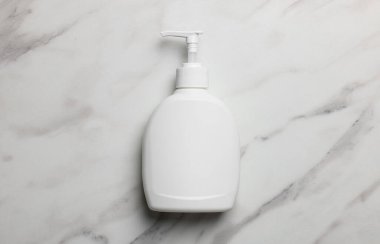 Dispenser of liquid soap on white marble table, top view