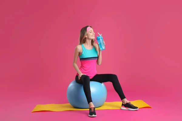 Beautiful Woman Sitting Fitness Ball Drinking Water Pink Background — Stockfoto