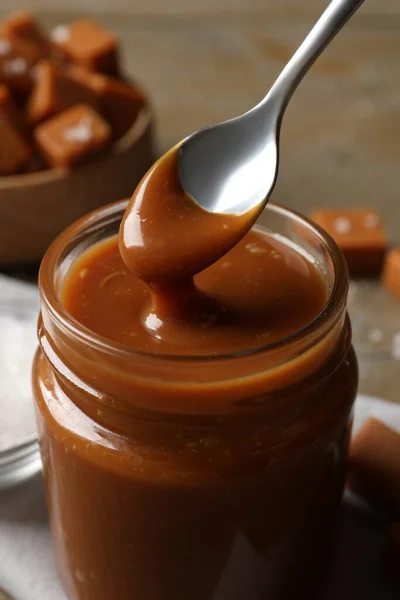 Taking Yummy Salted Caramel Spoon Glass Jar Table Closeup — Stockfoto