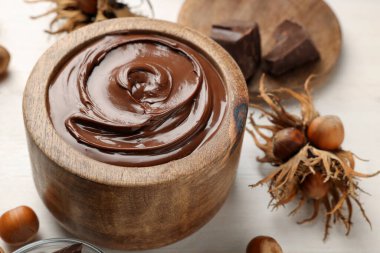 Beyaz ahşap masada fındıklı bir kase lezzetli çikolata ezmesi.