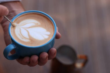 Barista, arka planda bulanık kahve fincanında desen oluşturuyor, yakın plan. Metin için boşluk