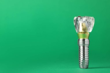 Educational model of dental implant on green background. Space for text