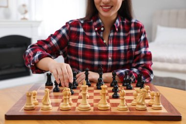 Woman playing chess at table in bedroom, closeup