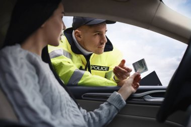 Kadın, arabanın camından polise rüşvet veriyor.