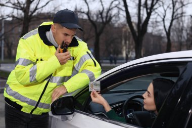 Kadın, arabanın camından polise rüşvet veriyor.
