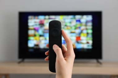 Televizyonda uzaktan kumandayla kanal değiştiren kadın, yakın çekim.