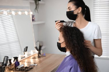 Müşteriyle kuaförde çalışan profesyonel stilist. Coronavirus karantinası sırasında kuaför servisi