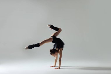 Beyaz arka planda amuda kalkan sevimli bir jimnastikçi.