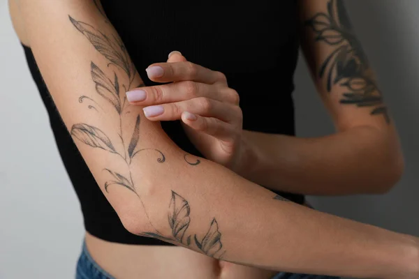 Mujer Aplicando Crema Brazo Con Tatuajes Sobre Fondo Claro Primer —  Fotos de Stock