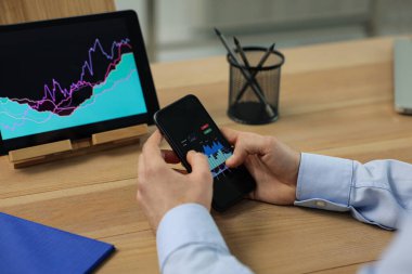 Broker with smartphone working in office, closeup. Forex trading