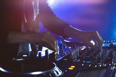 DJ, gece kulübünde modern konsol karıştırıcısında müzik yaratıyor.