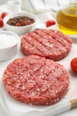 Raw hamburger patties with salt on board, closeup