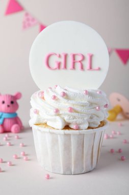 Beautifully decorated baby shower cupcake for girl with cream and topper on light background