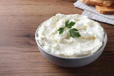 Tasty cream cheese with parsley on wooden table. Space for text