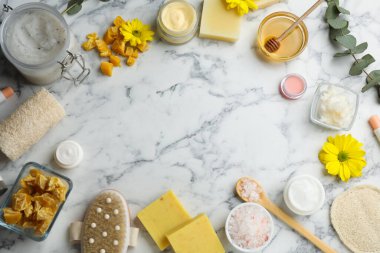 Frame made of beeswax and cosmetic products on white marble background, flat lay. Space for text