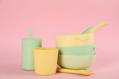Pembe arka planda plastik bulaşık takımı. Bebek maması servisi.