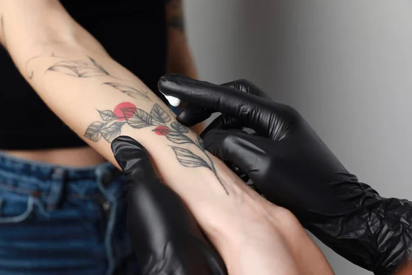 Trabajador Guantes Aplicando Crema Brazo Mujer Con Tatuaje Sobre Fondo — Foto de Stock