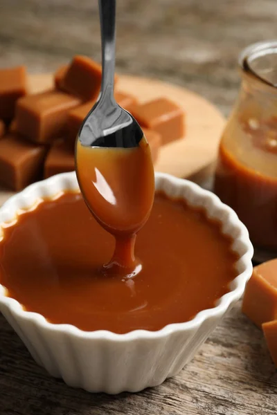 Taking Tasty Salted Caramel Spoon Bowl Wooden Table Closeup — Fotografia de Stock