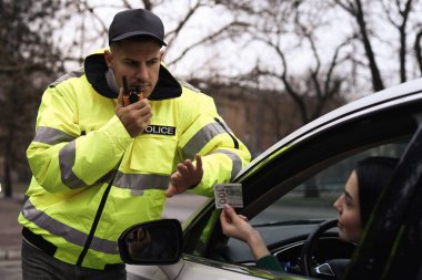 Polis memuru dışarıda arabanın yanında rüşvet vermeyi reddediyor.