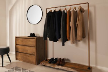 Modern giyinme odasının içinde şık kıyafetler, ayakkabılar ve ayna var.