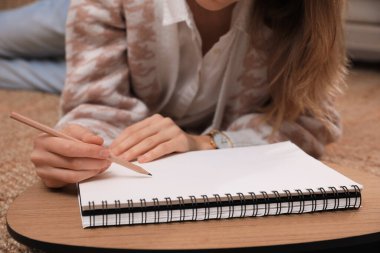 Çizim defterinde evde yere kalem çizen kadın, yakın plan.