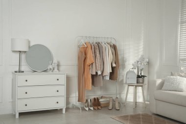 Modern giyinme odası. Şık kıyafetler, ayakkabılar ve güzel orkide çiçekleri.