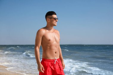 Kumsalda çekici vücutlu yakışıklı bir adam.