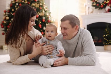 Mutlu bir aile ve yerde şirin bir bebek Noel için dekore edilmiş bir odada