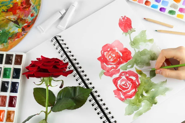 Γυναίκα Ζωγραφική Τριαντάφυλλα Μπλοκ Σκίτσο Λευκό Τραπέζι Top View — Φωτογραφία Αρχείου