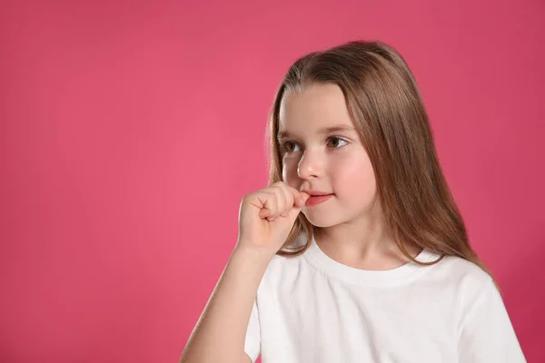 可爱的小女孩咬着她的指甲粉色背景 文字的空间 — 图库照片