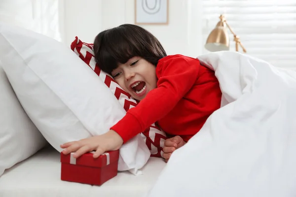 兴奋的小男孩在床上的枕头下找到了礼品盒 圣尼古拉斯日传统 — 图库照片