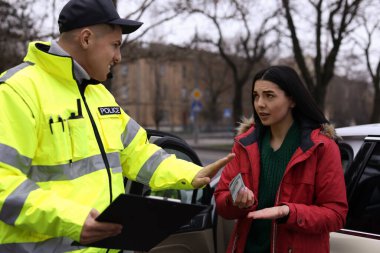 Polis memuru dışarıda arabanın yanında rüşvet vermeyi reddediyor.