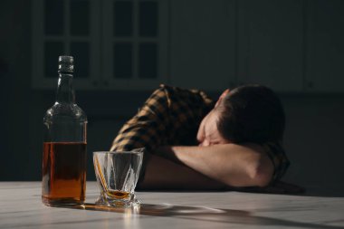 Mutfakta uyuyan bağımlı adam, alkollü içeceğe odaklan. Metin için boşluk