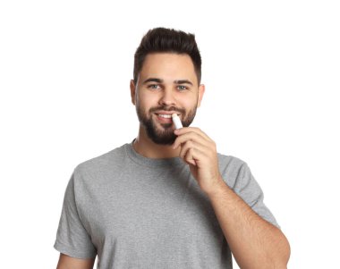 Genç adam beyaz arka plana dudak kremi sürüyor.