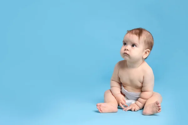 穿着尿布的可爱的小宝宝坐在浅蓝色的背景上 案文的篇幅 — 图库照片