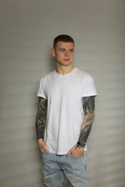 Giovane Uomo Con Tatuaggi Vicino Alla Parete Luminosa — Foto Stock